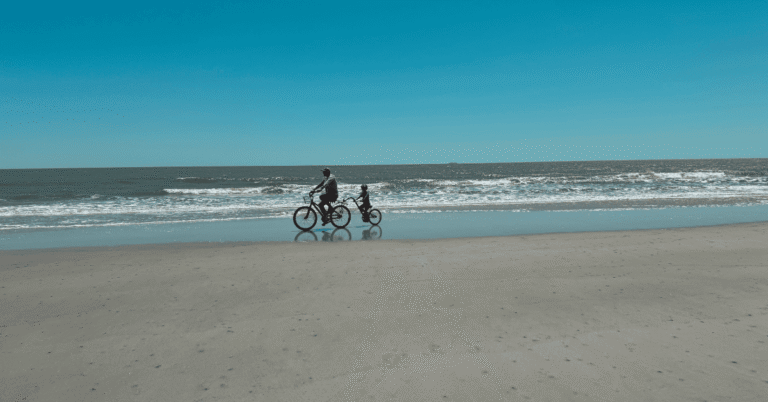Photo of dad and child riding tandem bike on the beach on Hilton Head Island. Featured image for blog post: Renting Bikes on Hilton Head Island with Kids.