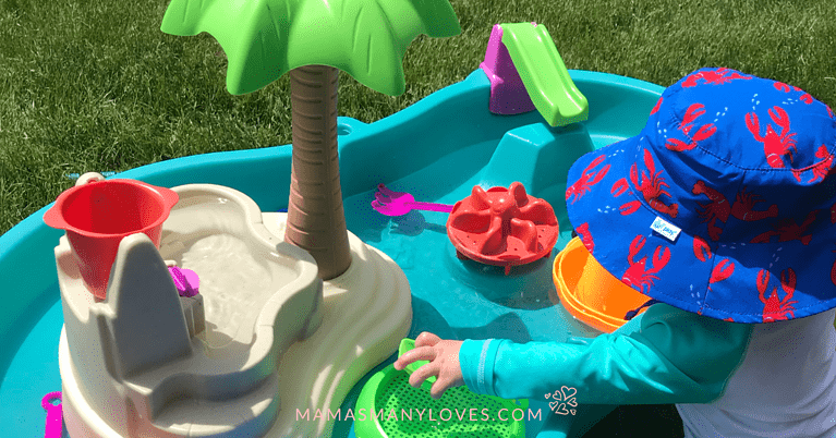 Baby wearing sun hat playing in water table.
