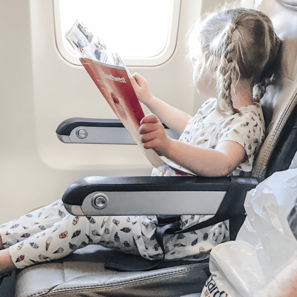 Photo of toddler on airplane reading safety magazine